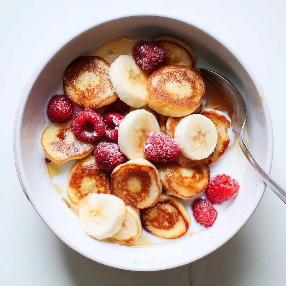 Delicious mini pancake cereal nestled in a bowl, perfect with fresh berries and syrup.  