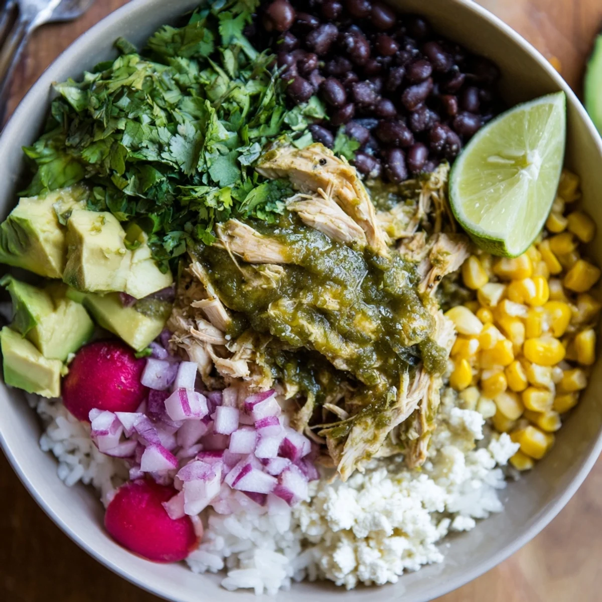 A colorful green enchiladas rice bowl topped with fresh avocado and cheese.  
