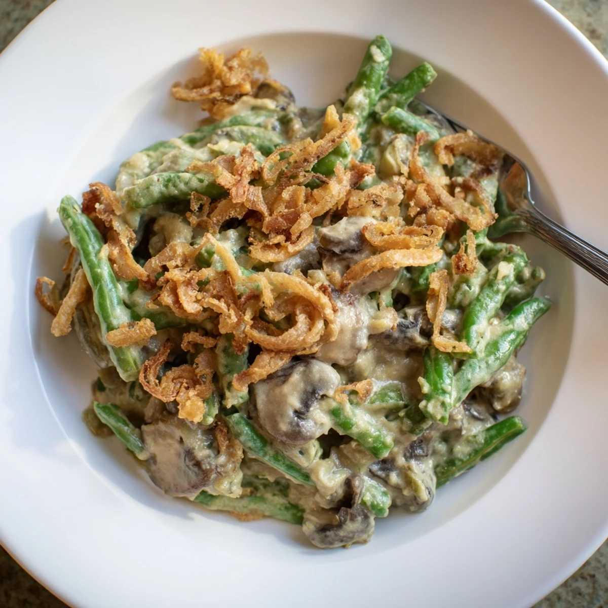 Classic Old-School Green Bean Casserole topped with crispy fried onions and creamy sauce.  