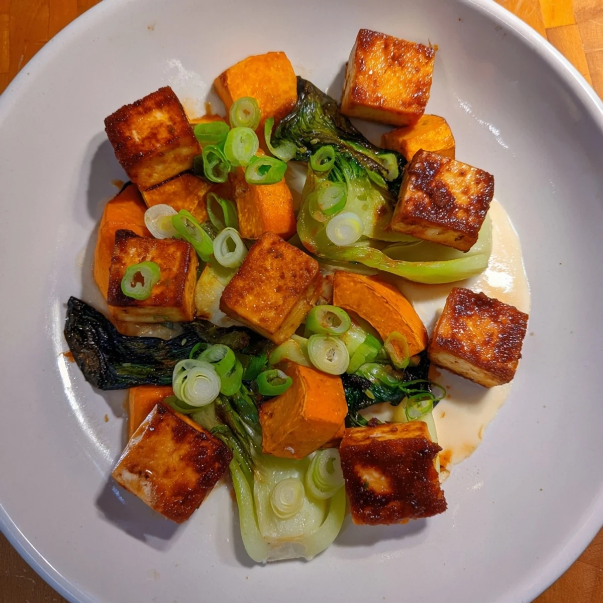 Golden-brown miso-glazed tofu and winter squash alongside tender bok choy, a delicious vegan dish.