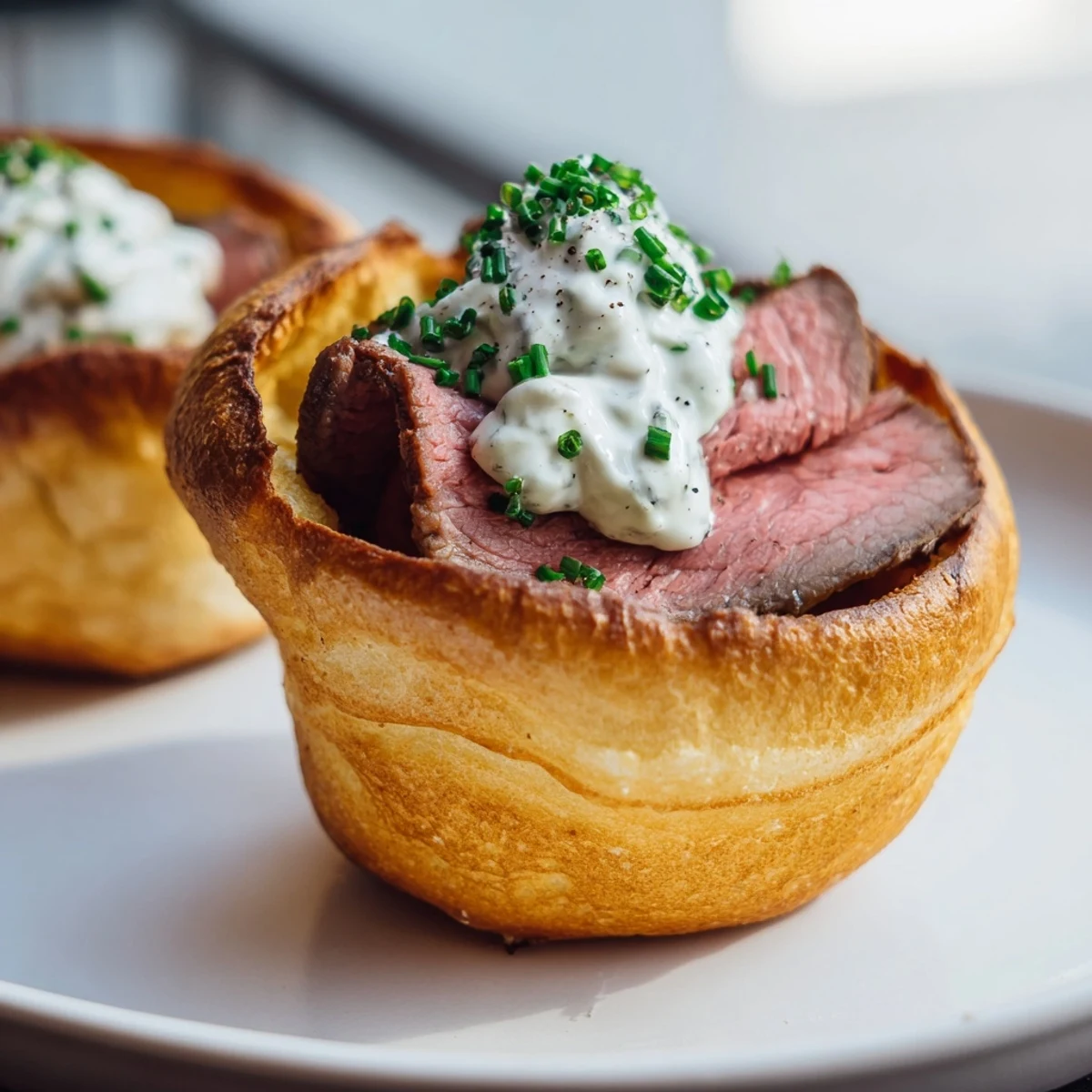 Mini Express Holiday Yorkshire Pudding Bites showcasing crisp, brown batter, cradling horseradish-topped roast beef.
