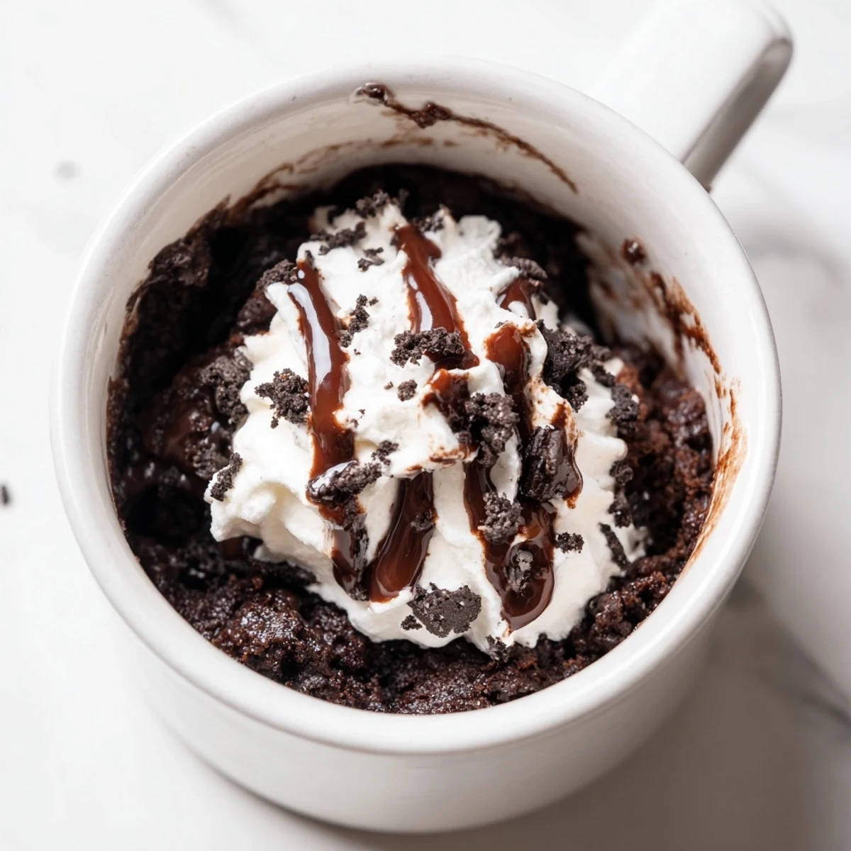 A warm, single-serving Oreo mug cake with melting chocolate chips, perfect for a treat.