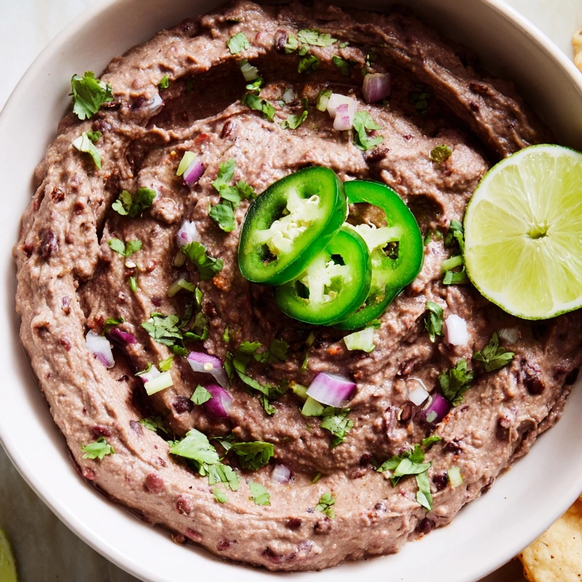 A vibrant photo showcasing this Spicy Black Bean Dip, ready to serve with optional crumbled cheese and lime wedges.