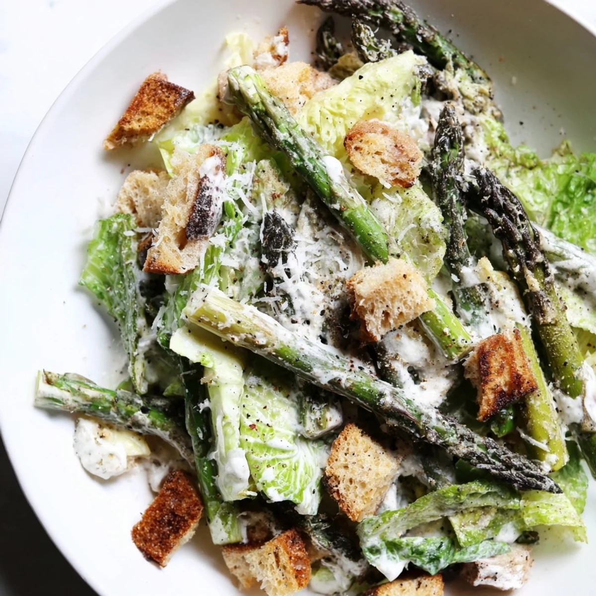 Fresh Roasted Asparagus Caesar Salad with creamy yogurt dressing and shaved Parmesan garnish.