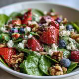 Crumble creamy goat cheese and toasted walnuts over a colorful Spinach and Berry Salad Bowl, perfect for a light, refreshing lunch.