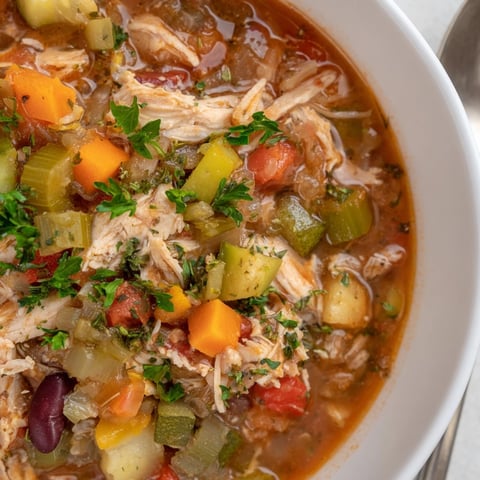 Close-up shot of flavorful Cajun Turkey Veggie Soup, garnished with fresh parsley.