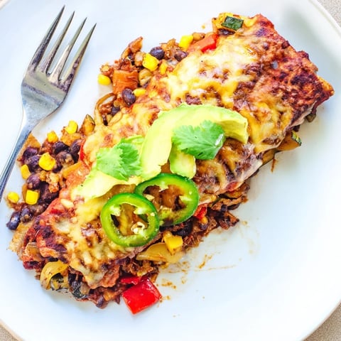 Colorful Farmers Market Vegetarian Enchiladas topped with melted cheese and fresh avocado slices.  
