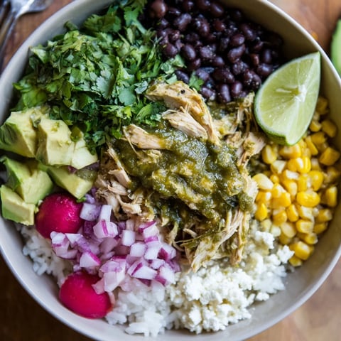A colorful green enchiladas rice bowl topped with fresh avocado and cheese.  