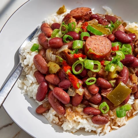 A steaming bowl of Red Beans & Rice topped with bright green onions.  