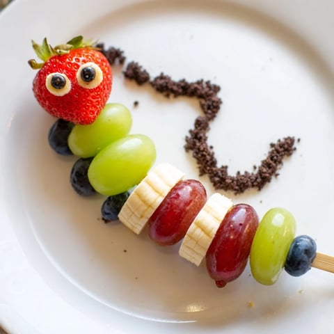 Vibrant Caterpillar Fruit Skewer Track with colorful fruit on a cookie crumb trail, perfect snack.