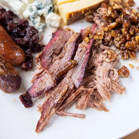 Smoky BBQ & Bourbon Companion charcuterie board filled with tender meats, cheeses, and candied pecans.
