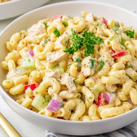 A vibrant bowl of Chicken Macaroni Holiday Salad, filled with creamy dressing and colorful vegetables.