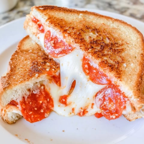 Golden-brown Pizza Grilled Cheese sandwich, oozing melted mozzarella cheese, ready to be enjoyed.