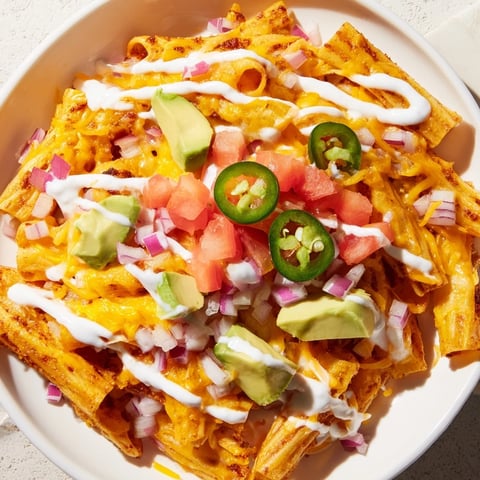Crispy golden Pasta Chips Nachos loaded with melted cheese, fresh toppings, and a creamy sauce.