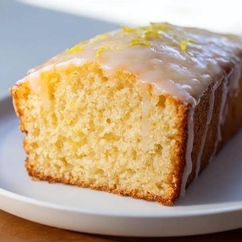 Fluffy lemon yogurt cake with a glistening glaze, perfect for a cozy afternoon treat.