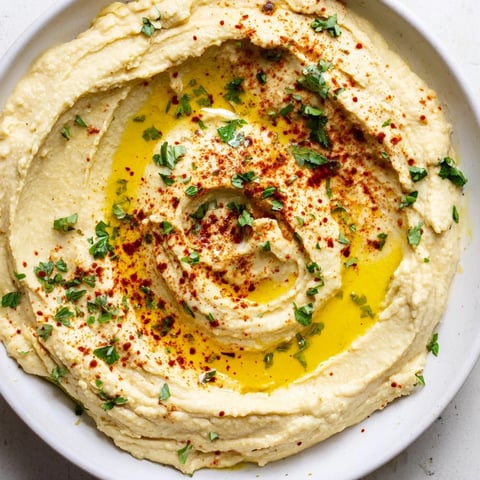 Creamy Levantine hummus plate drizzled with olive oil and paprika, ready to be scooped with pita bread.