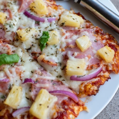 Close-up of homemade Hawaiian Pizza: melted cheese, ham, pineapple on delicious crust.
