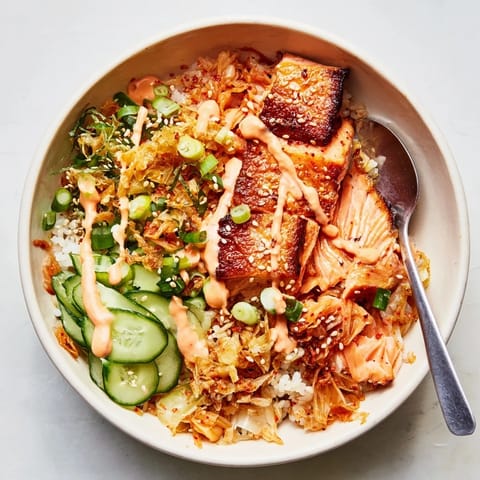 A vibrant crispy salmon rice bowl served with garlic, cucumbers, and sesame seeds.  