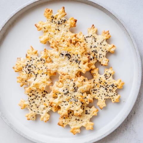Golden gourmet crackers shaped like snowflakes, ready to be served on an inviting cheese board.