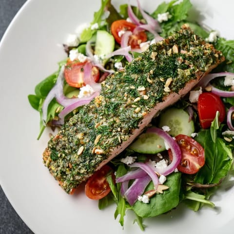 Golden, baked herb-crusted salmon atop a colorful salad, drizzled with zesty vinaigrette.