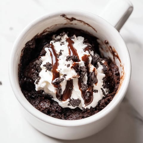 A warm, single-serving Oreo mug cake with melting chocolate chips, perfect for a treat.