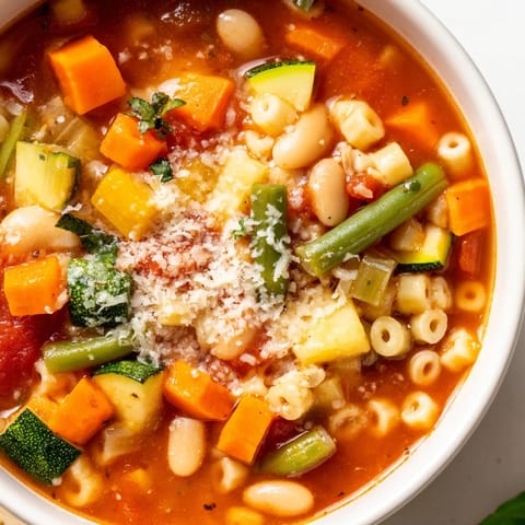 A close-up of hearty Tomato Basil Minestrone, filled with vegetables and pasta, ready to eat.