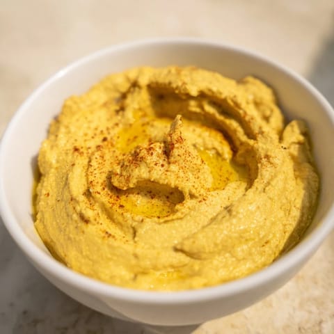 Smooth, golden Chickpea Curry Paste garnished with a swirl of olive oil, perfect for dipping.