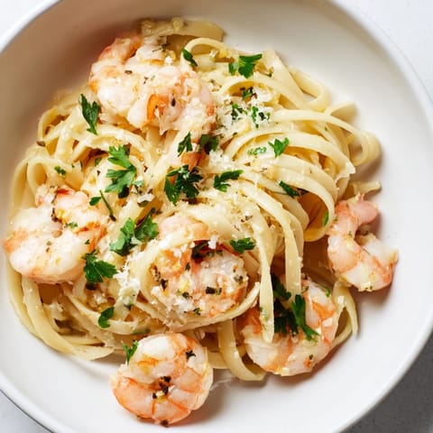 A skillet of Creamy Garlic Shrimp Pasta glistens, plump shrimp nestled among silky noodles, a lemon wedge brightening the rich, parmesan-laced sauce.