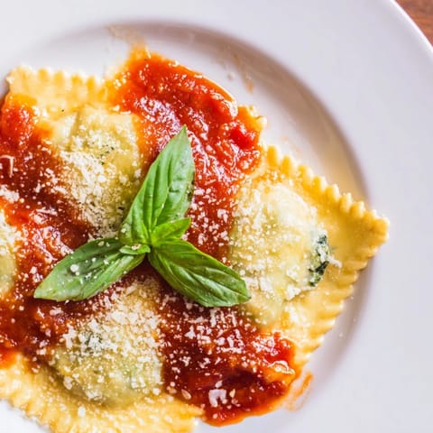 Close-up on cooked Spinach Ricotta Ravioli in a red marinara sauce, showcasing the pasta texture and melted cheese.  