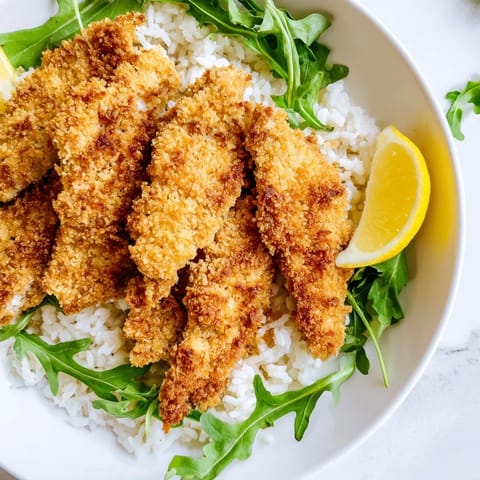 Golden, crispy Parmesan-coated chicken cutlets served warm over a bed of white rice with peppery arugula and lemon.