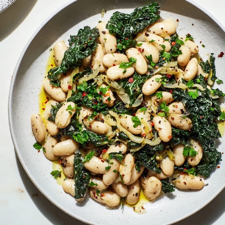 Hearty garlicky beans and greens, plated and garnished, offering a taste of comfort on a plate.