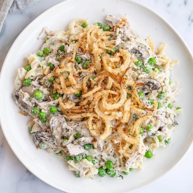 A close-up of a creamy Homemade Tuna Noodle Casserole topped with crispy fried onions.