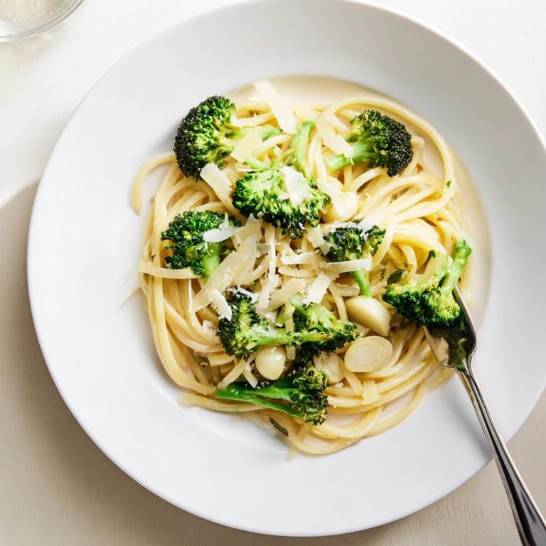 Freshly grated Parmesan and lemon zest top this easy One-Pot Lemon Broccoli Pasta, served steaming in a shallow bowl.