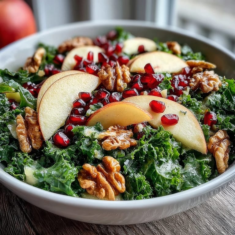 Two beautiful servings of a Kale and Pomegranate Bowl featuring tender greens, crisp apple slices, ruby-red seeds, and chopped walnuts ready for a healthy lunch or side dish.