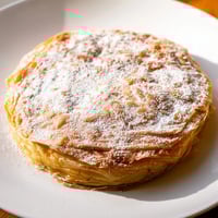 Golden and flaky Moroccan Pastilla Pie, a savory meat pie dusted with powdered sugar, ready to serve.
