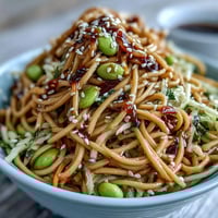 Fresh sesame ginger noodle bowl with cold soba noodles, crisp cabbage, and colorful vegetables in a tangy dressing.  